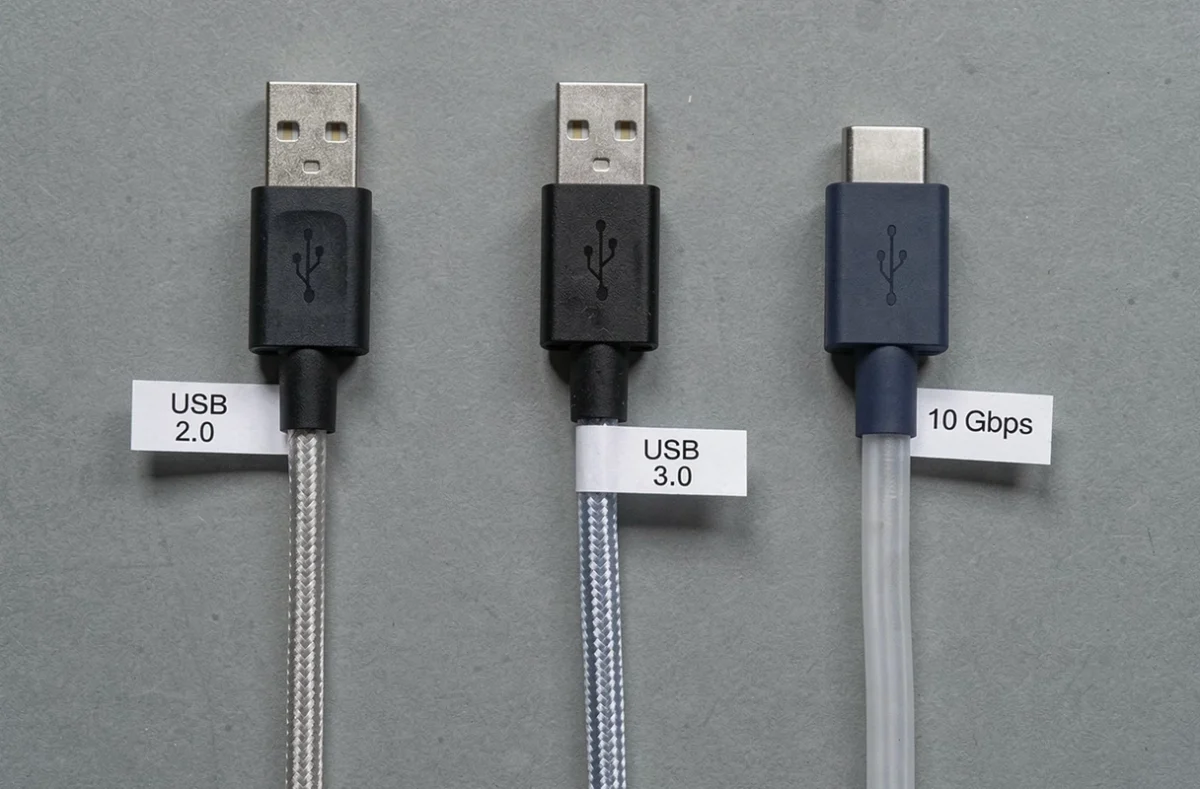 Comparaison de trois câbles USB B vers USB C USB 2.0 3.0 et 10 Gbps disposés côte à côte en vue à plat